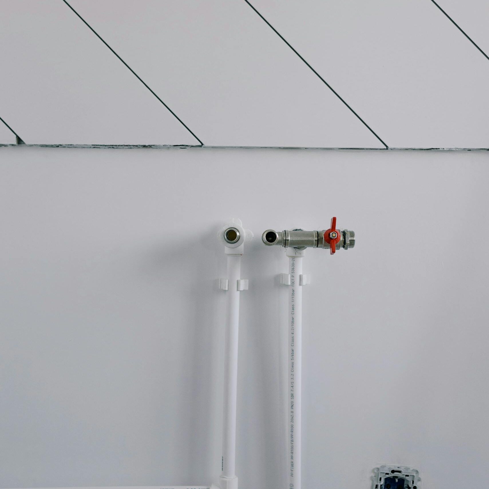 White wall with minimalist plumbing pipes and diagonal lines